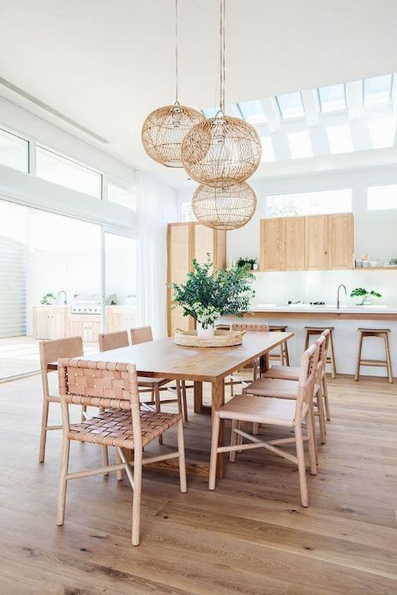 Woven leather chairs, light colored wood and roudn wicker lampshades over the dining space make it feel beachy