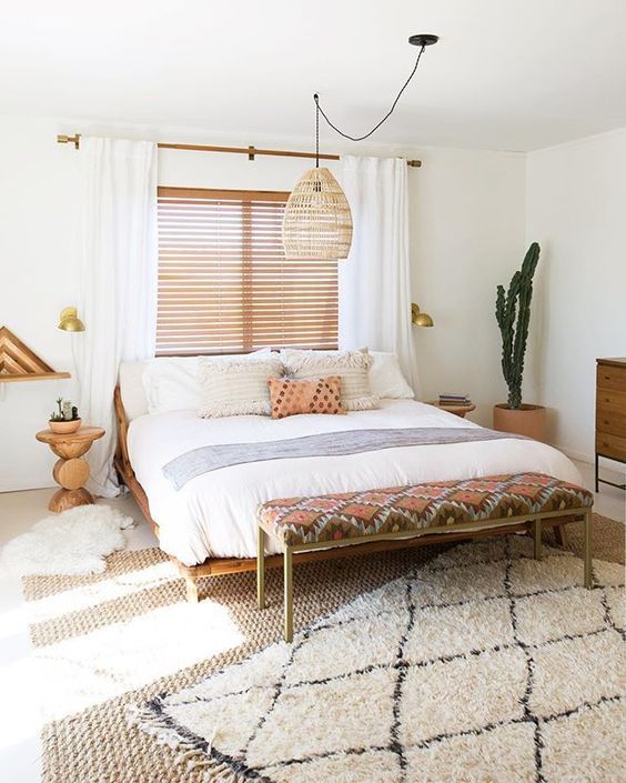 a desert boho bedroom with a wicker lamp over the bed to highlight its relaxed boho styling