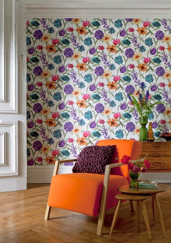 A colorful floral wallpaper wall matches the mid century modern space and cheers it up at the same time