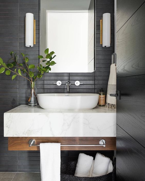 a contemporary bathroom with matte black skinny tiles on the wall plus a floating wood and marble vanity