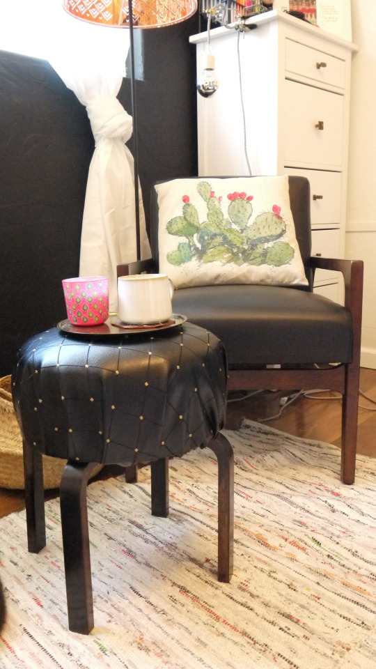 an IKEA Frosta stool turned into a chic small ottoman covered with black leather with a shiny touch