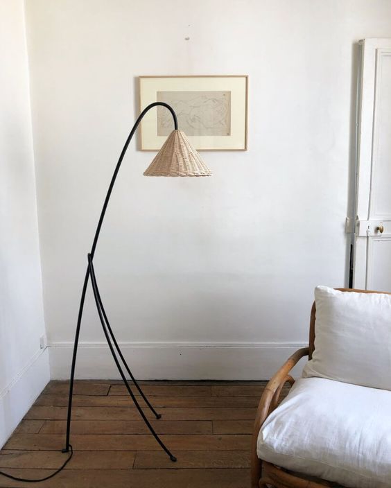 a catchy black metal floor lamp with a tiny wicker lampshade for a natural and coastal feel in the space