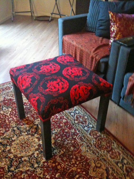 an IKEA Lack table renovated with bright black and red printed fabric on top to use as a footstool or ottoman
