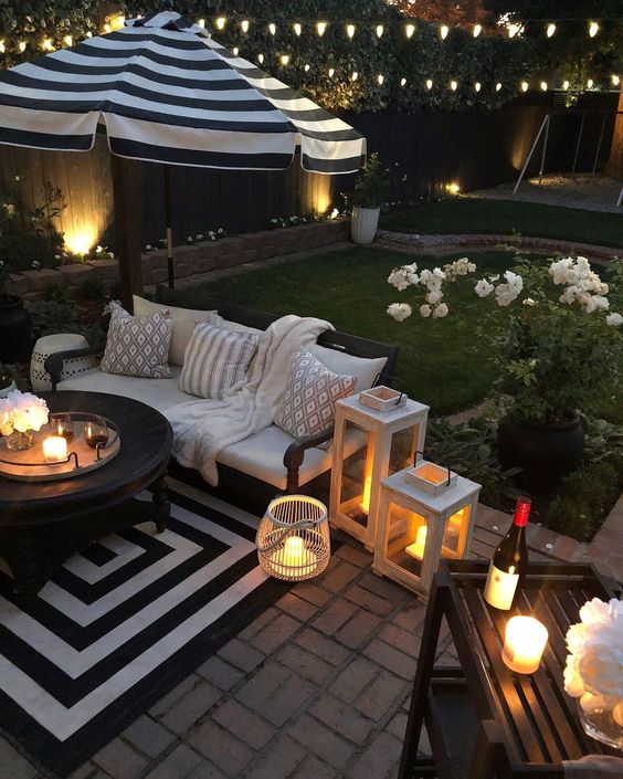 a cozy patio with a striped rug, candle lanterns and potted blooms that refresh the look