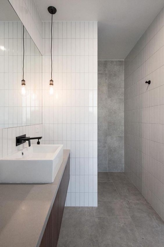 A minimalist bathroom done with grey tiles and white skinny ones for an eye catchy touch