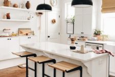 20 bold dark metal and light-stained wood stools add a touch of drama to the neutral kitchen and pendant lamps continue that