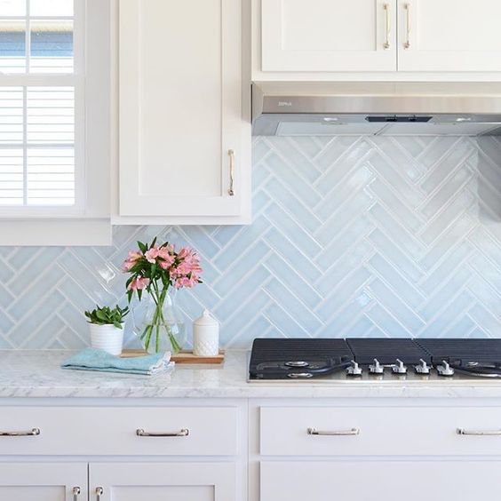 light blue skinny tiles done in a chevron pattern add both pattern and color to the space and make it catchier