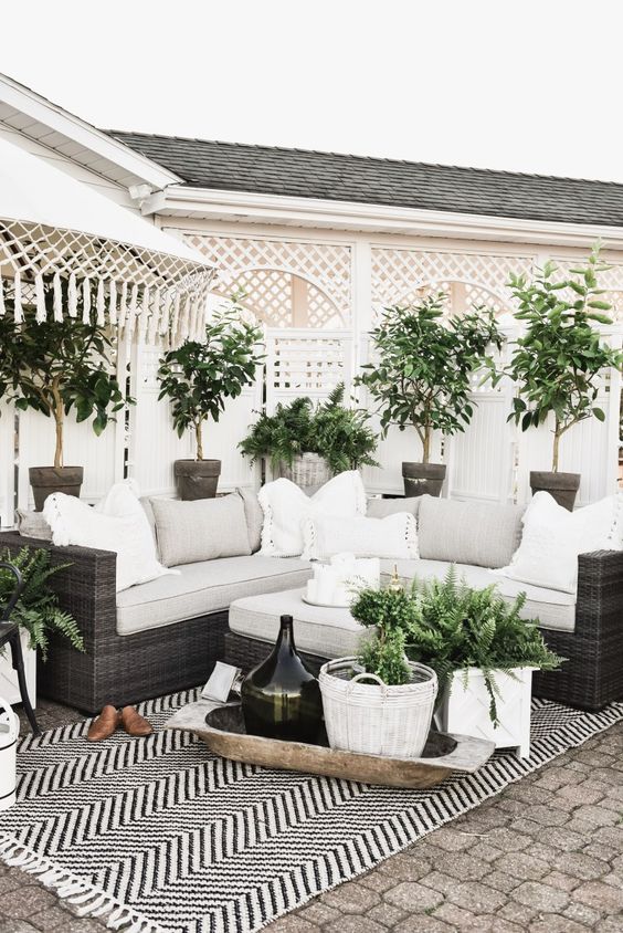 a chic farmhouse patio with potted greenery, a chevron rug, neutral pillows for a polishing touch