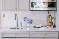24 vintage grey kitchen cabinets and marble skinny tiles done in a chevron pattern for more eye-catchiness