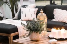 25 a chic patio decorated with contrasting blankets and pillows, candle lanterns and potted greenery