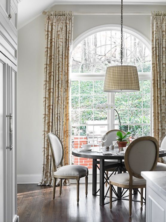 a formal meets farmhouse dining space with a large arched window that brings light inside