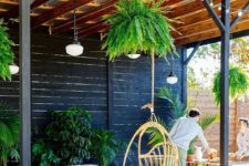 26 a bright patio with potted greenery, colorful pillows, a hanging rattan chair and pendant lamps