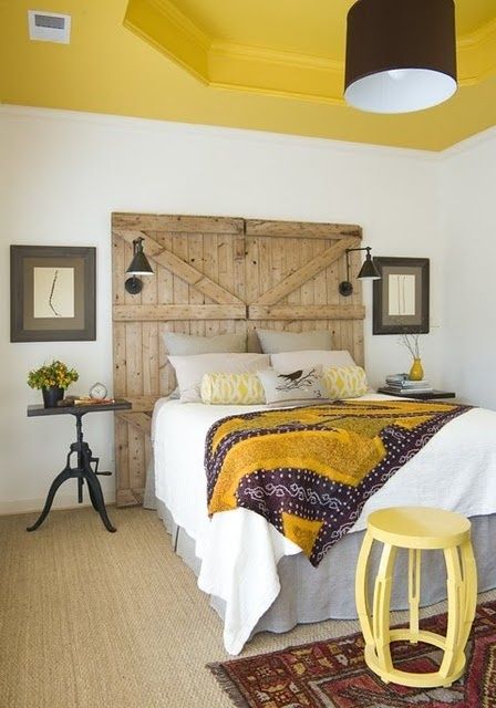 a rustic meets modern bedroom with a bright yellow ceiling and a matching blanket and a side table