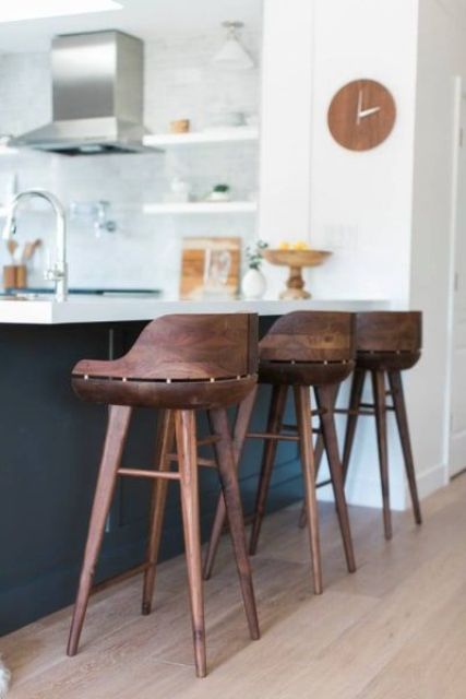 very eye-catchy dark stained wooden stools contrast the black and white kitchen island and look rich