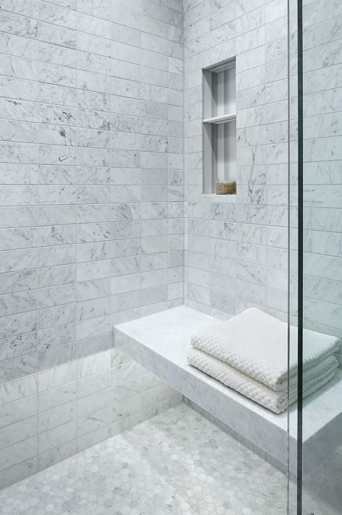a Carrara marble shower space with a floating bench and nches in the wall is a chic and bright idea