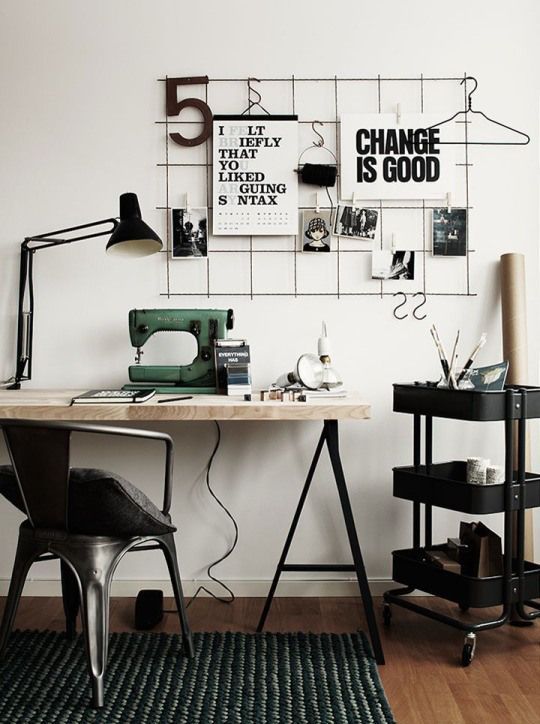 a black and white Scandinavian home office with a grid with notes, a trestle desk, an IKEA Raskog cart and lamps