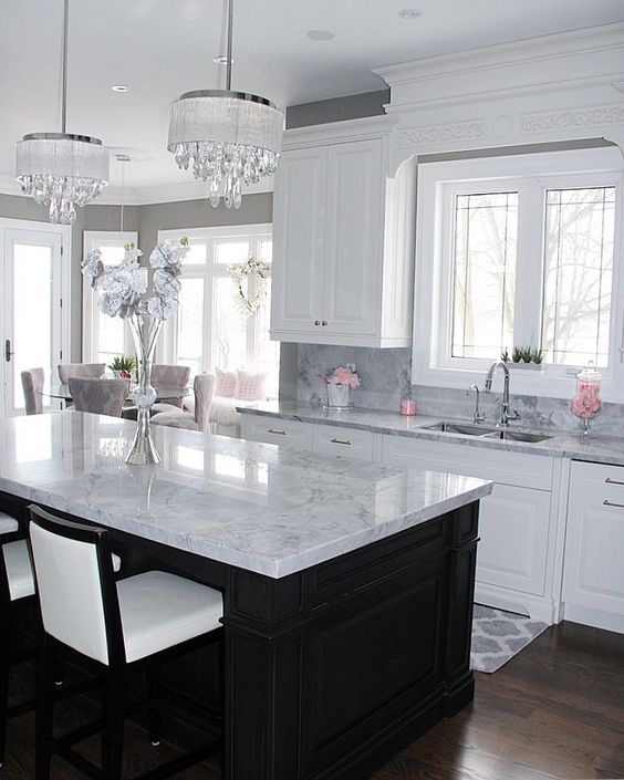 a black kitchen island and white cabients are covered with the same neutral stone countertops for a cohesive look