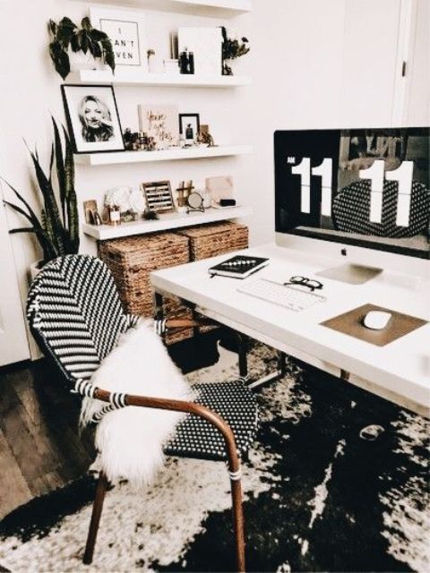 a boho black and white home office with an abstract rug, a white desk and shelves, a rattan chair and baskets for storage