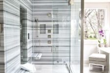 a bold modern shower space done with blue striped marble and two floating benches that don’t take much space