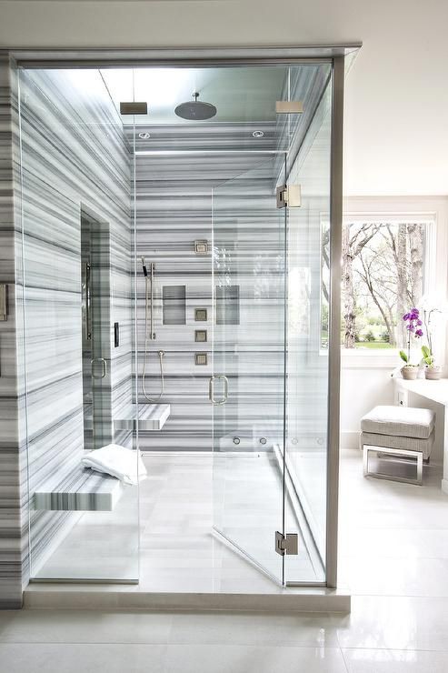 a bold modern shower space done with blue striped marble and two floating benches that don't take much space