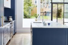 a bright and fresh blue kitchen with white stone countertops and brass hardware looks very chic