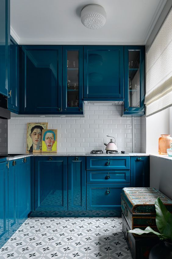a bright blue kitchen with a white stone countertop and a white subway tile backsplash for a highly contrasting look