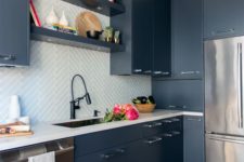 a contemporary blue kitchen with white countertops and a white tile backsplash clad with a pattern