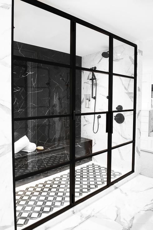 a gorgeously dramatic black and white shower space with black framed doors and a black marble wall plus a built-in bench