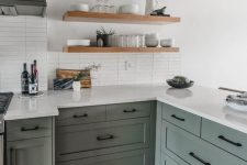 a light green farmhouse kitchen with black fixtures and white stone countertops and a white stacked tile backsplash