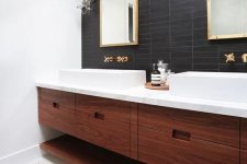 a mid-century modern bathroom with black skinny tiles on the accent wall that contrast white sinks