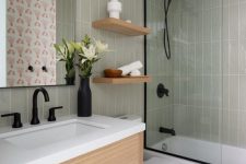 a mid-century modern bathroom with grey skinny tiles, a timber vanity and shelves, black fixtures and white appliances