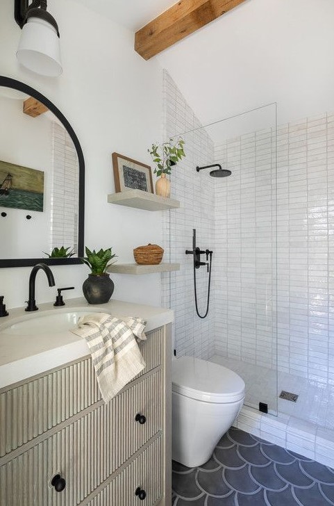 A mid century modern bathroom with white stacked tiles, wooden beams, a ribbed vanity and black fixtures