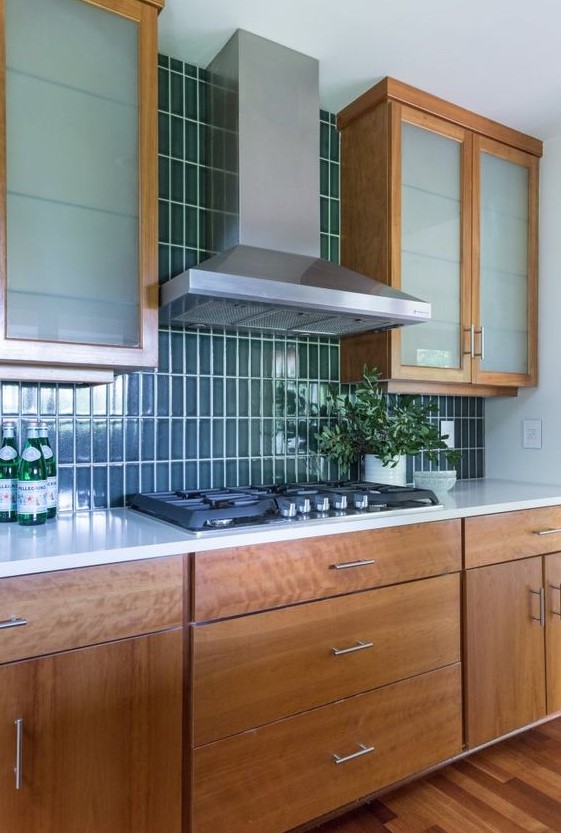 a mid-century modern wooden kitchen with a glossy blue stacked tile backsplash and frosted glass cabinets