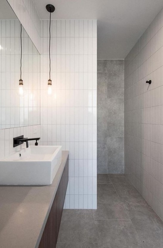 A minimalist bathroom done with grey tiles and white skinny ones for an eye catchy touch