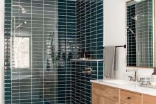 a modern Scandinavian bathroom with teal skinny and grey marble tiles, a timber vanity, a mirror and cool lamps