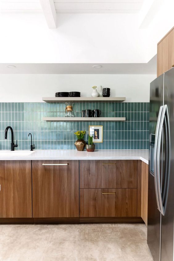 a modern kitchen with MDF cabinets, white stone countertops, a green skinny tile backsplash, open shelves and black fixtures
