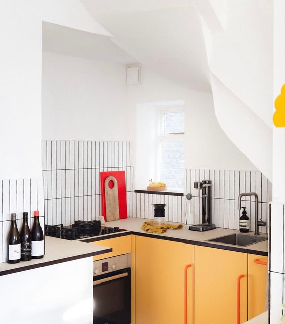 a modern small kitchen with yellow cabinets, countertops, a white skinny tile backsplash and black grout