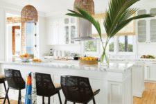 a modern tropical kitchen with white cabinets, marble countertops, wicker lampshades, black chairs and wicker shades