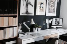 a moody contemporary home office with a black statement wall, a white desk, artworks and a shelving unit