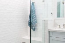 a pure white shower space with a floating bench and a marble tile floor plus seamless glass doors looks ethereal