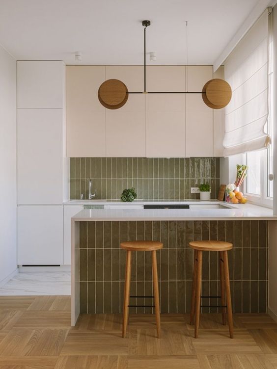 a serene kitchen with neutral cabinets, green skinny tiles cladding the backsplash and the base of the kitchen island