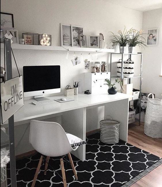 a simple black and white home office with a printed rug, white furniture, a metal shelving unit