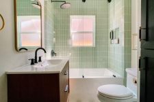 a small and cool mid-century modern bathroom with skinny green tiles, a printed tile floor, a stained vanity, white appliances