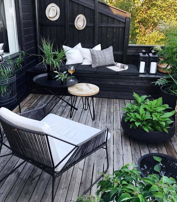 A small boho inspired black and white deck with modern furniture, pillows, potted greenery to refresh the space