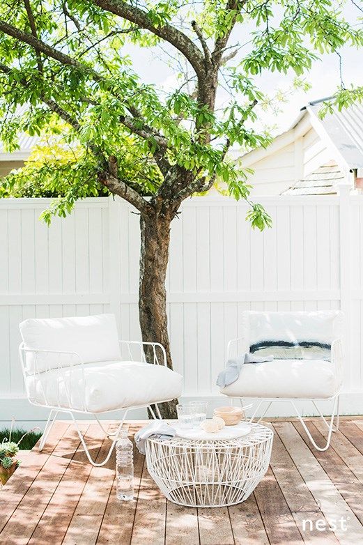 a small deck with a living tree, simple and stylish white furniture and a coffee table to serve meals