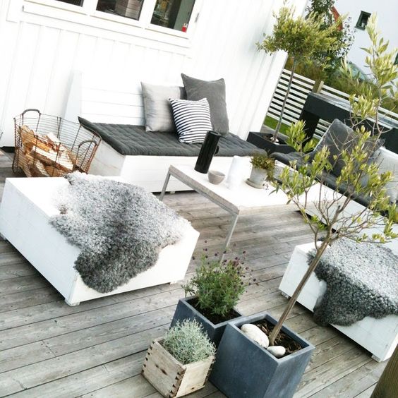 a small weathered wood deck with contemporary furniture, potted greenery and blooms and screen for privacy