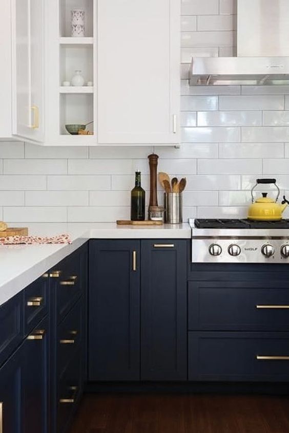 a trendy two tone kitchen with white and black cabinets, white countertops and gold hardware plus a white subway tile backsplash