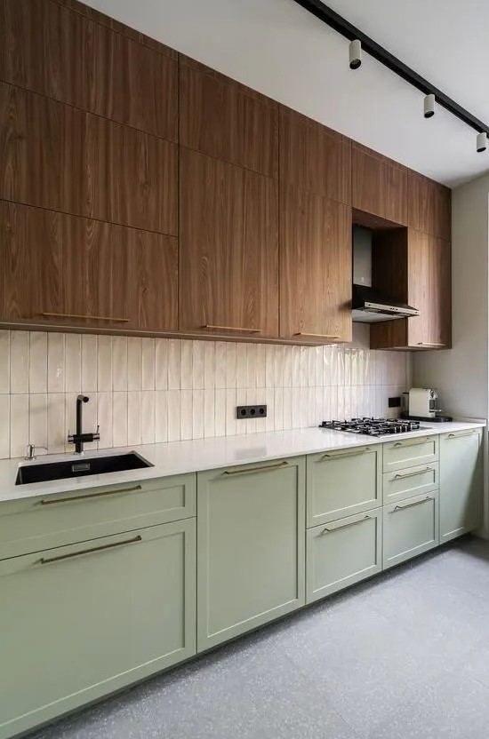 A two tone kitchen with timber and sage green cabinets, a white skinny tile backsplash and white countertops plus black fixtures