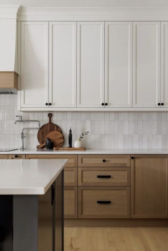 A two tone kitchen with white and stained cabinets, a white skinny tile backsplash and black handles is amazing