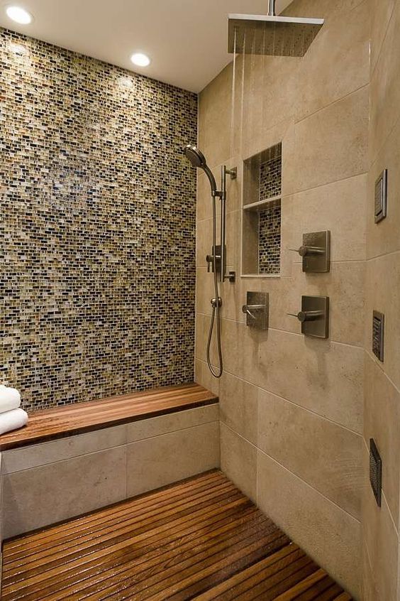 a welcoming earthy shower with various types of tiles that match, a teak floor and a built-in bench with a teak seat